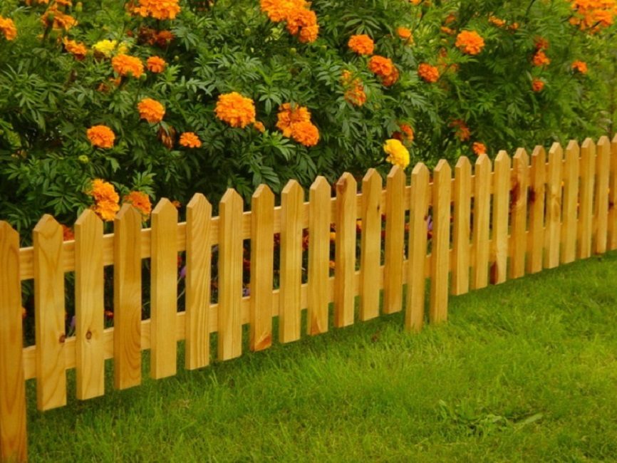 La valla de madera más simple para un macizo de flores es una valla clásica.